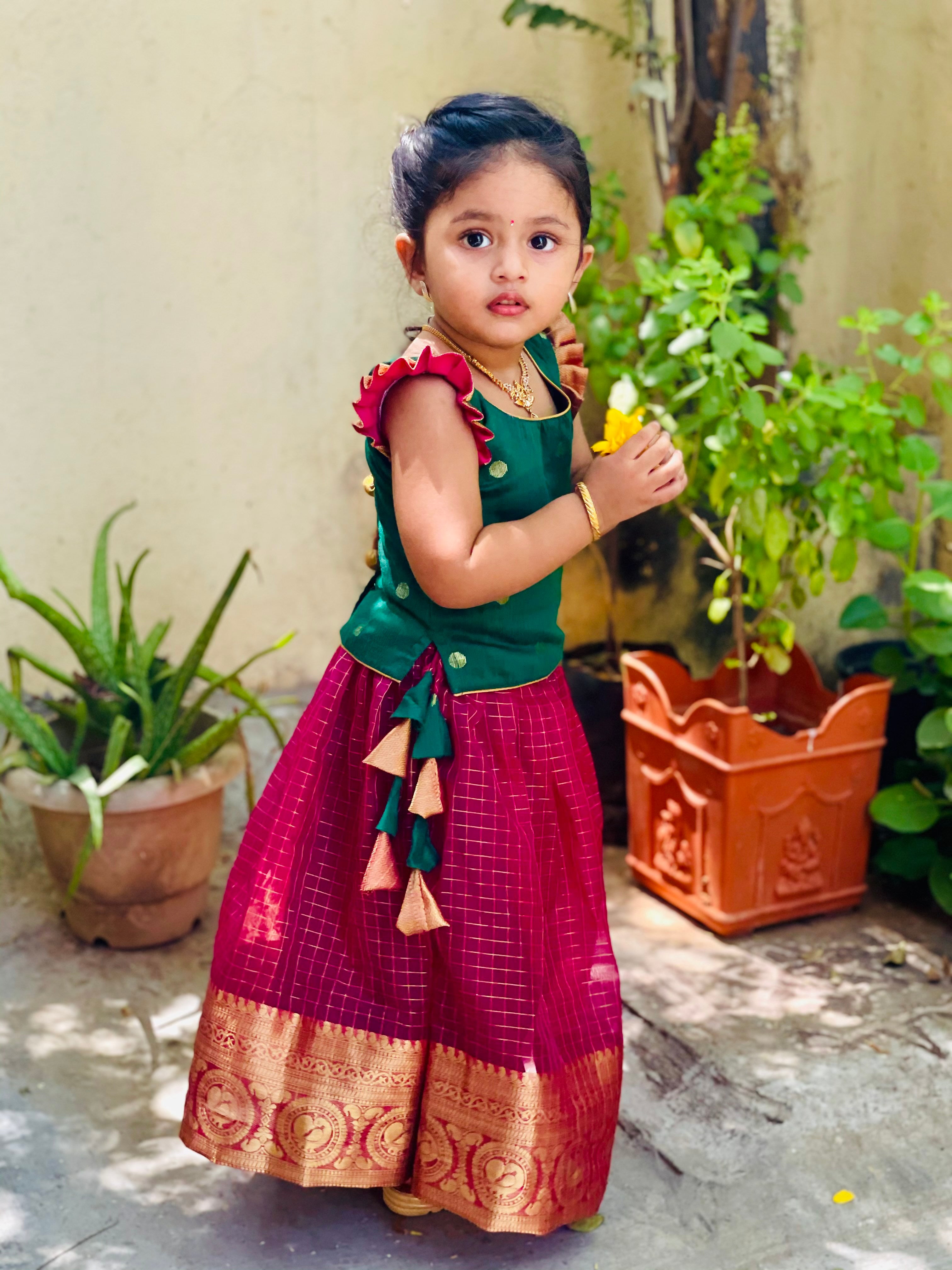 Shop green and pink traditional Pattu Pavadai for girls. Get the perfect south Indian dress for girls and find the perfect design with zari checks and colors. Shop online for cotton and designer baby clothes with Ekanta studio now!